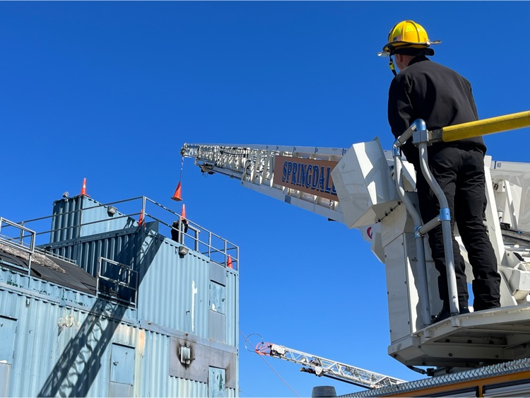 Firefighter using an aerial to place a road cone for an aerial exercise